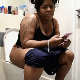 A big, black, British woman texts on her phone while sitting on a toilet. Plops and pissing is heard. She wipes her ass and shows us the dirty TP. Presented in 720P HD. About 4 minutes.